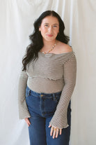 Model wearing the asymmetrical off the shoulder striped top with a pair of basic dark denim and a pop of color in the necklace. Top has lettuce hem detail on the sleeves and a fitted look. 