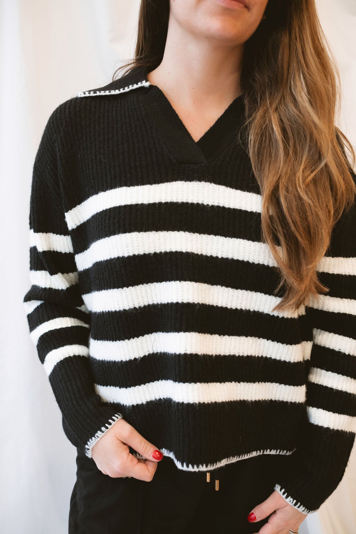 Black striped knit sweater top for women featuring a collared V-neckline, contrasting trim, and classic preppy-inspired design for elevated everyday styling.