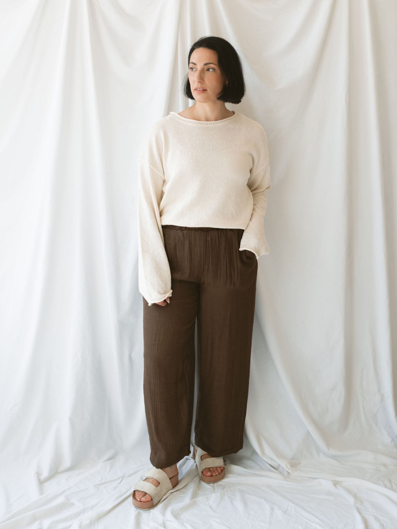 Model wearing brown linen blend pants with elastic waistband. 