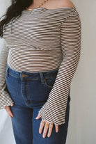 Model wearing the asymmetrical off the shoulder striped top with a pair of basic dark denim and a pop of color in the necklace. Top has lettuce hem detail on the sleeves and a fitted look. 