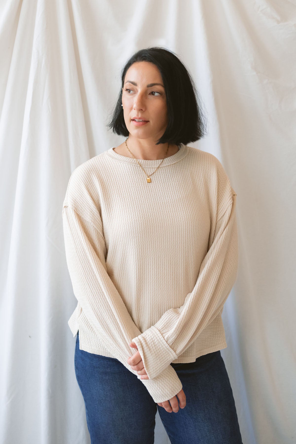 Model wearing a textured exposed seam long sleeve top in a natural color.