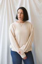 Model wearing a textured exposed seam long sleeve top in a natural color.