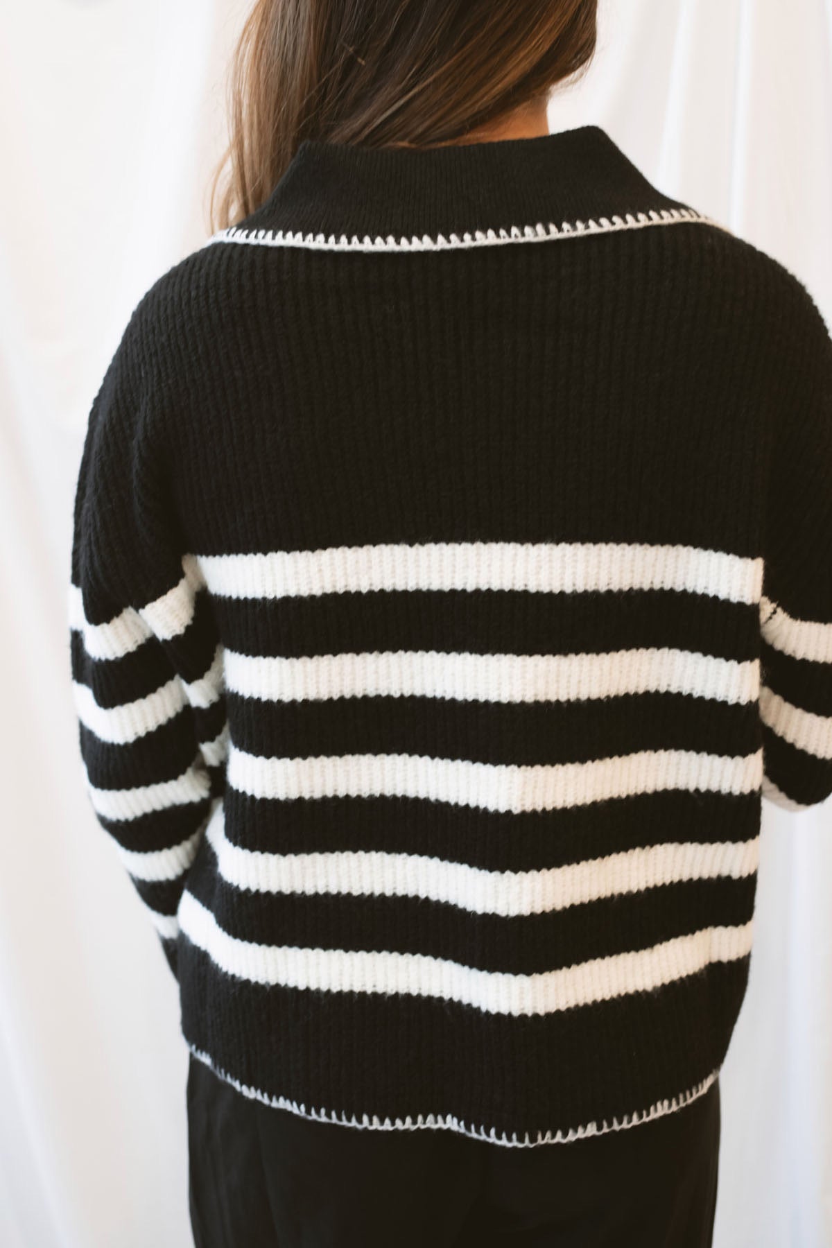 Black striped knit sweater top for women featuring a collared V-neckline, contrasting trim, and classic preppy-inspired design for elevated everyday styling.