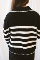 Black striped knit sweater top for women featuring a collared V-neckline, contrasting trim, and classic preppy-inspired design for elevated everyday styling.