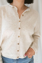 Close up view of model wearing button up cardigan in color oat. This cardigan is easy to wear open and layered over a variety of tanks and shirts or you can wear it buttoned up as a top.