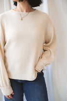 Model wearing a textured exposed seam long sleeve top in a natural color.