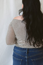 Model wearing the asymmetrical off the shoulder striped top with a pair of basic dark denim and a pop of color in the necklace. Top has lettuce hem detail on the sleeves and a fitted look. 