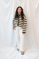 Model is wearing oversized striped button down cardigan in olive and cream. 