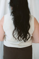 Model wearing sleeveless beige turtleneck. 
