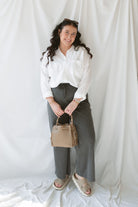 Model wearing the long sleeve white button up top. Model has shirt styled fully buttoned and tucked into the Mila wide leg pants. This outfit is easy and casual but still feels put together. 