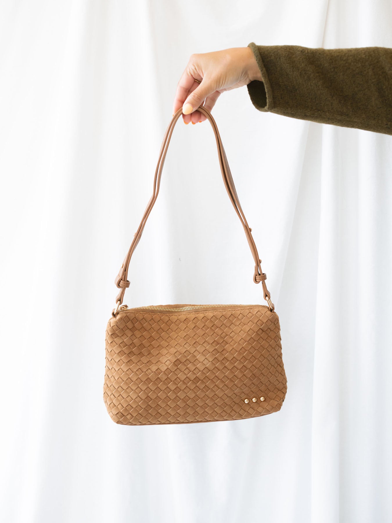 Model holding woven slouch bag with adjustable shoulder strap. 