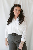 Model wearing the long sleeve white button up top. Model has shirt styled fully buttoned and tucked into the Mila wide leg pants. This outfit is easy and casual but still feels put together. 
