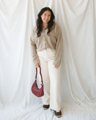 Model holding crescent shaped bag, so you can see strap and front view of bag. 