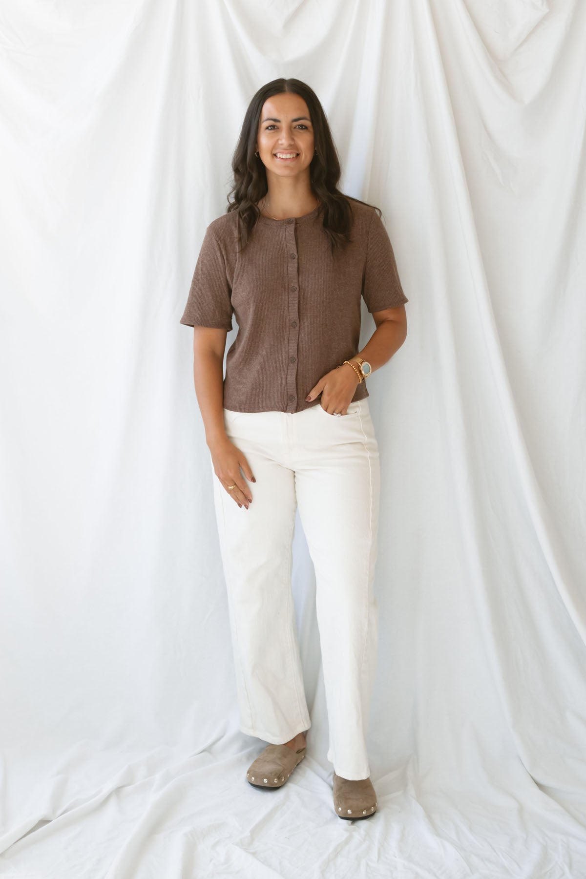 Model is wearing the ribbed short sleeve cardigan in brown. Model has it paired with an off white denim pant for a cassic and timeless look.