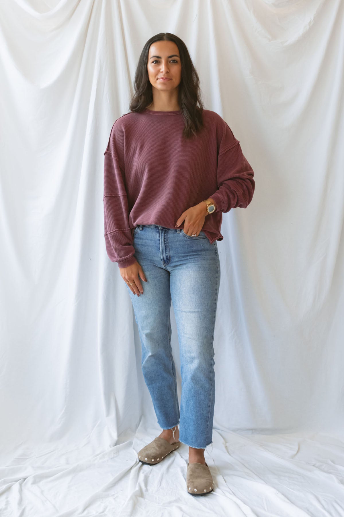 Model wearing exposed seam detail long sleeve top in a light maroon color.