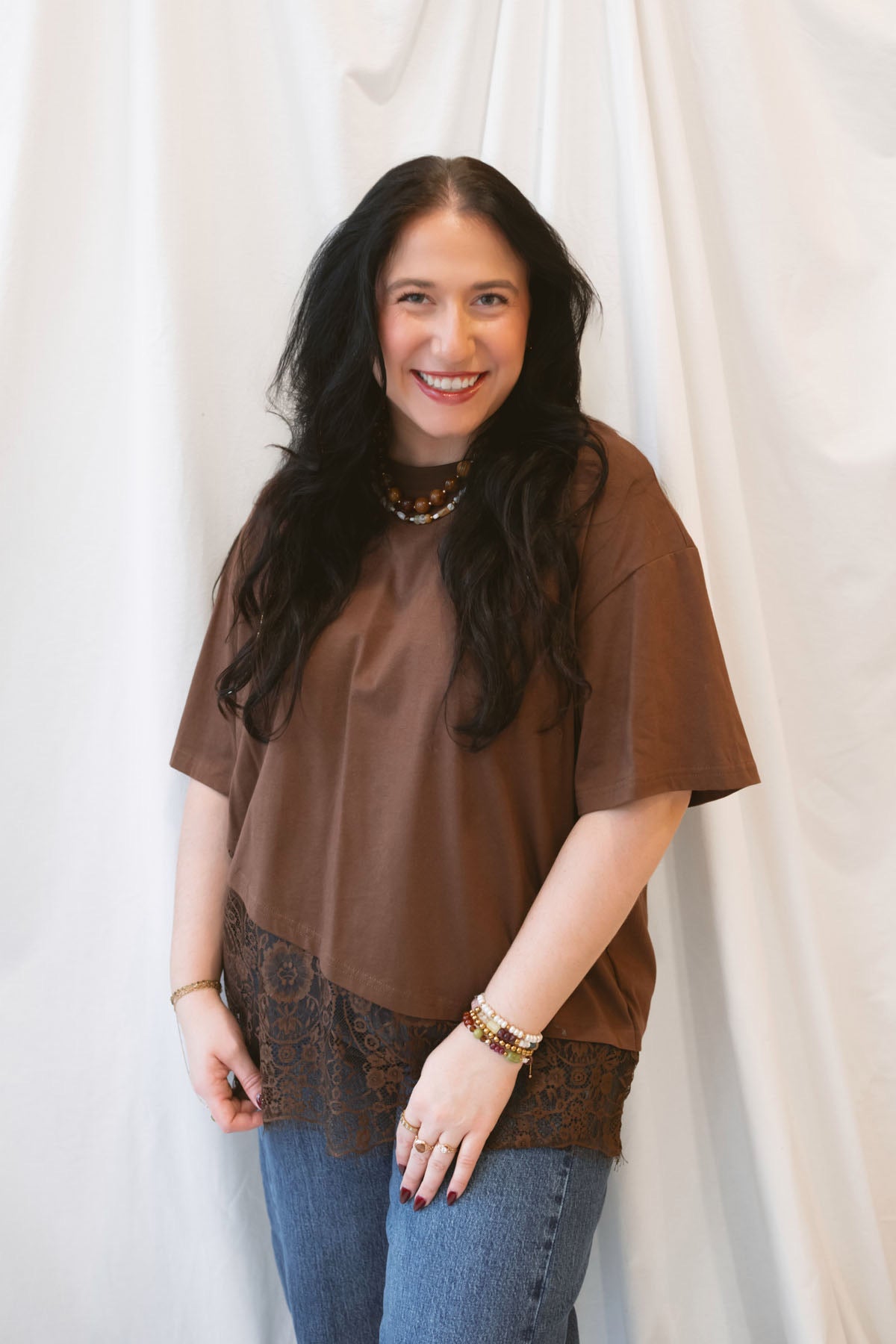 Chocolate brown women's t-shirt featuring delicate floral lace trim and an asymmetrical silhouette for a feminine, elevated everyday look.