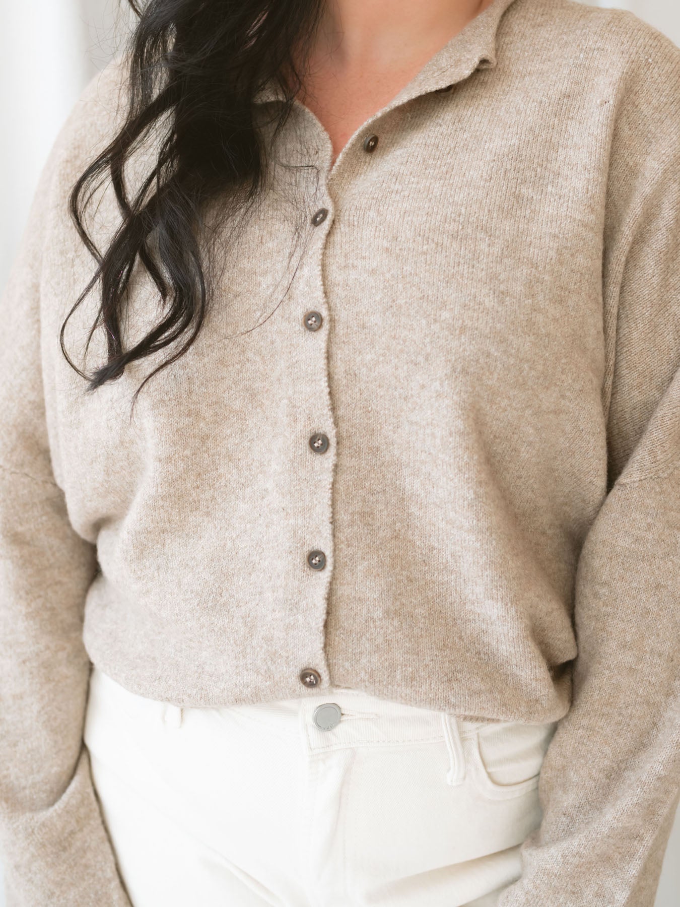 Model wearing full button cardigan in light mocha. Cardigan is a great versatile option because you can wear it fully buttoned as a sweater or open and layered as a cardigan. 