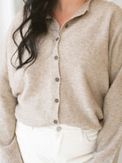 Model wearing full button cardigan in light mocha. Cardigan is a great versatile option because you can wear it fully buttoned as a sweater or open and layered as a cardigan. 
