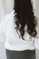 Back view of model wearing the long sleeve white button up top. Model has shirt styled fully buttoned and tucked into the Mila wide leg pants. This outfit is easy and casual but still feels put together. 