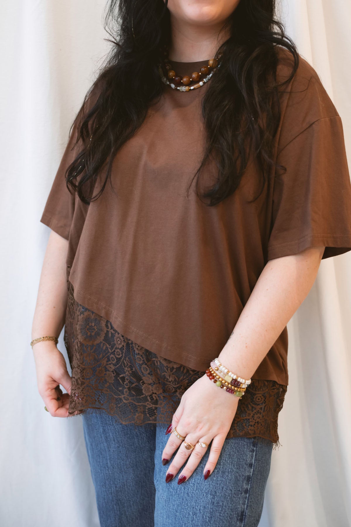 Chocolate brown women's t-shirt featuring delicate floral lace trim and an asymmetrical silhouette for a feminine, elevated everyday look.