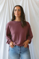 Model wearing exposed seam detail long sleeve top in a light maroon color.