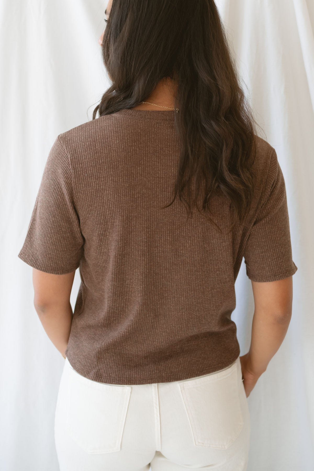 Model is wearing the ribbed short sleeve cardigan in brown. Model has it paired with an off white denim pant for a cassic and timeless look.