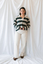 Model wearing rugby style top in green and grey. 