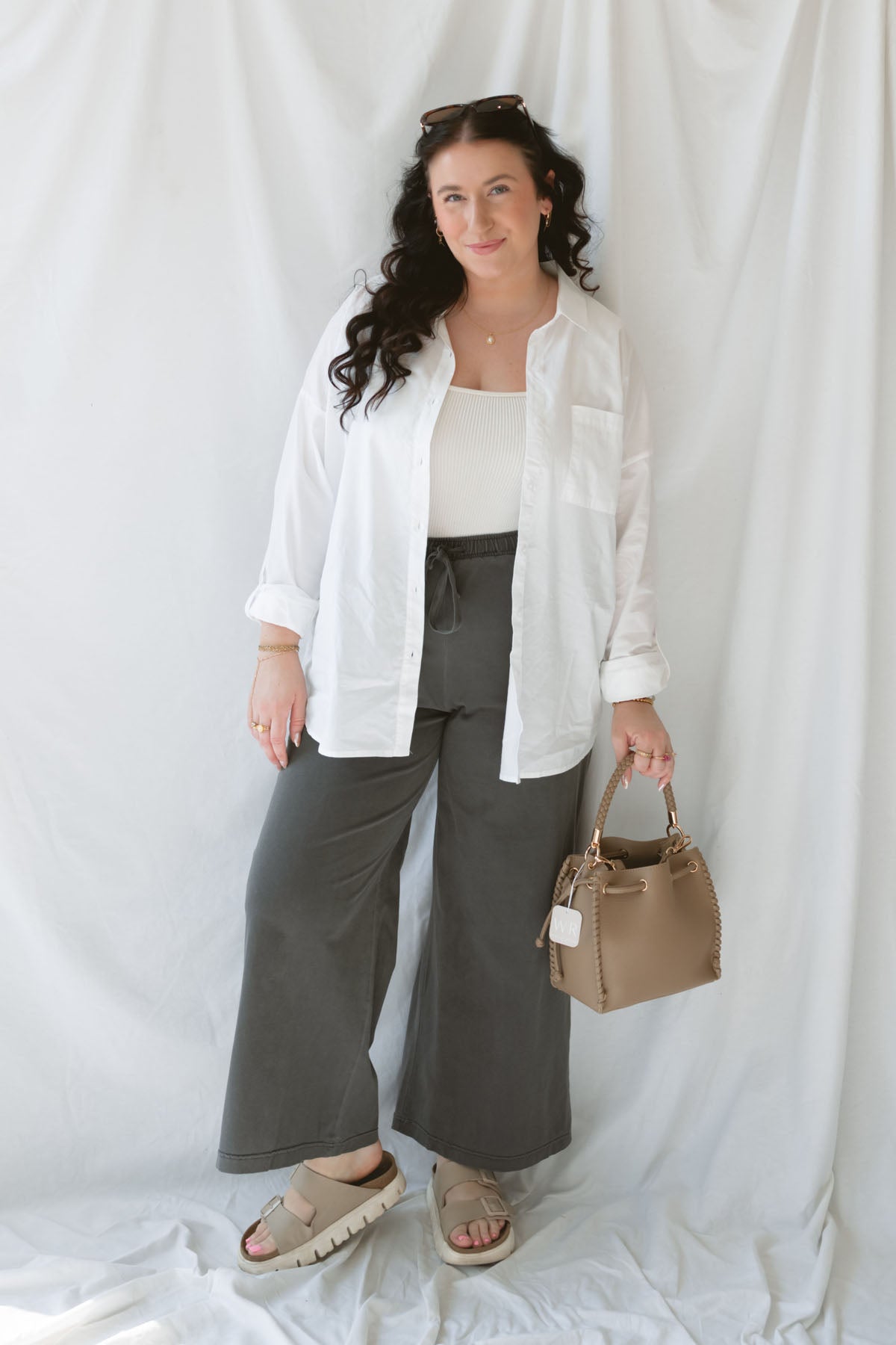 Model wearing the long sleeve white button up top. Model has it styled all the way open over a tank and paired with the Mila wide leg pants in charcoal. This outfit is easy and casual but still feels put together. 