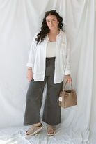 Model wearing the long sleeve white button up top. Model has it styled all the way open over a tank and paired with the Mila wide leg pants in charcoal. This outfit is easy and casual but still feels put together. 