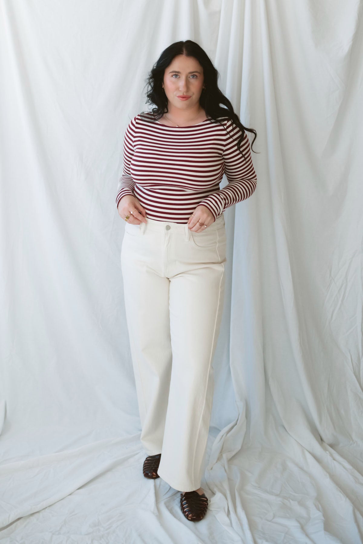 Model wearing long sleeve boat neck style striped top. 