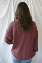 Model wearing exposed seam detail long sleeve top in a light maroon color.