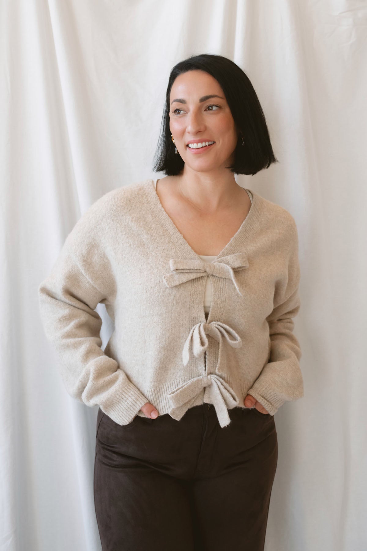 Kayla light taupe knit sweater with a reversible ribbon bow detail, styled with the bow in front.
