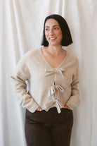 Kayla light taupe knit sweater with a reversible ribbon bow detail, styled with the bow in front.