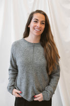 Grey knit sweater for women featuring a softly rolled neckline, center seam detailing, and a classic relaxed silhouette for everyday fall and winter styling.