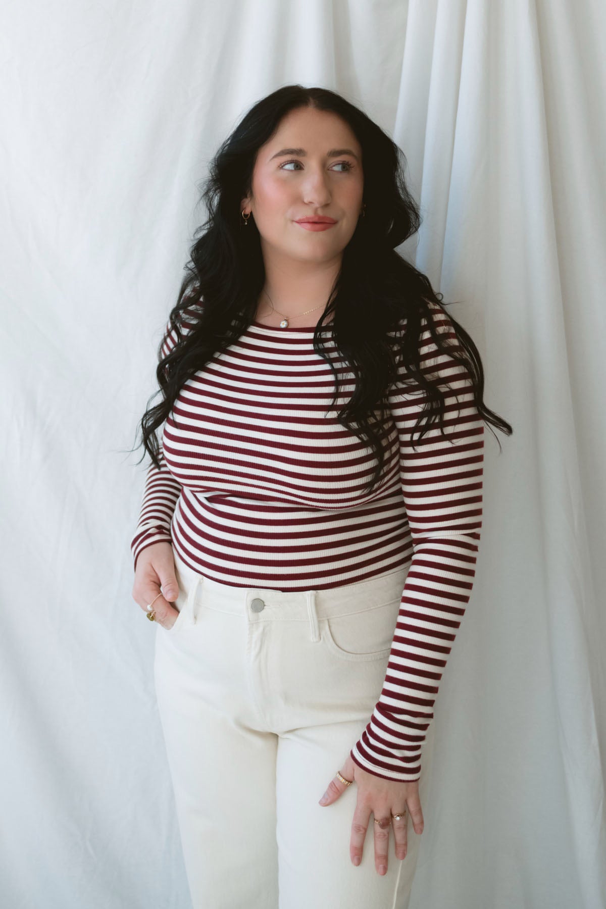 Model wearing long sleeve boat neck style striped top. 