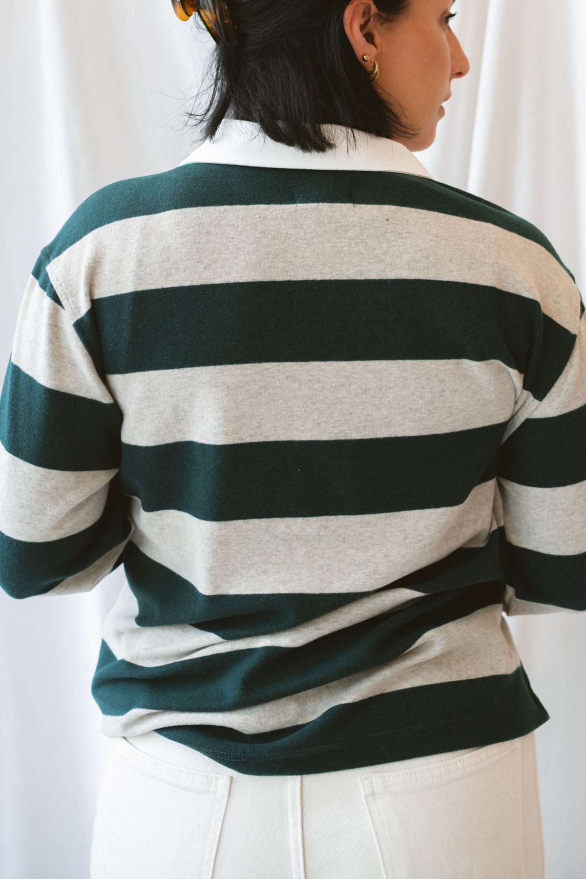 Model wearing rugby style top in green and grey. 