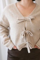 Kayla light taupe knit sweater with a reversible ribbon bow detail, styled with the bow in front.