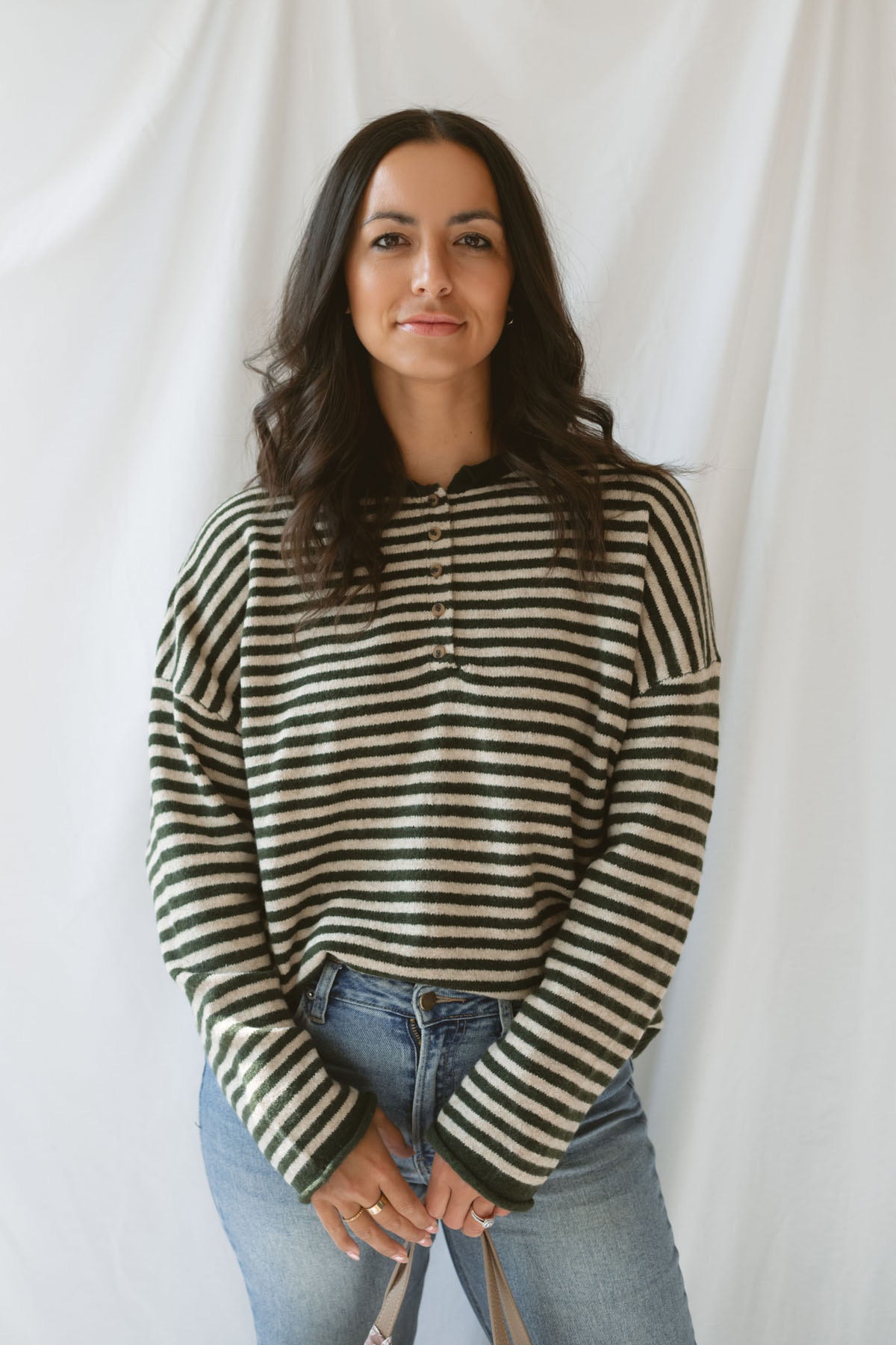 Model wearing the olive striped long sleeve henley sweater. 
