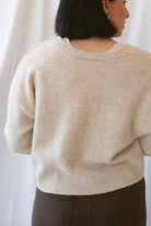 Kayla light taupe knit sweater with a reversible ribbon bow detail, styled with the bow in front.