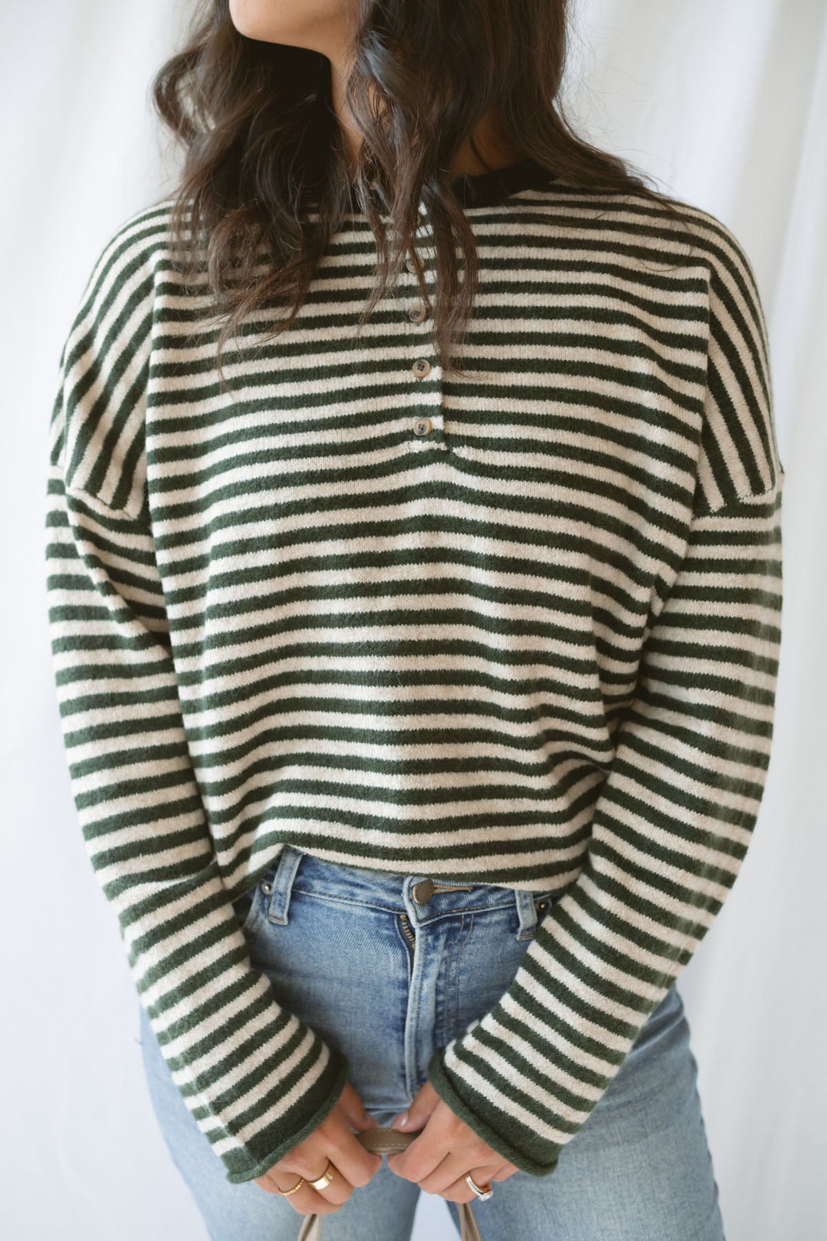 Model wearing the olive striped long sleeve henley sweater. 