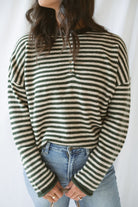 Model wearing the olive striped long sleeve henley sweater. 