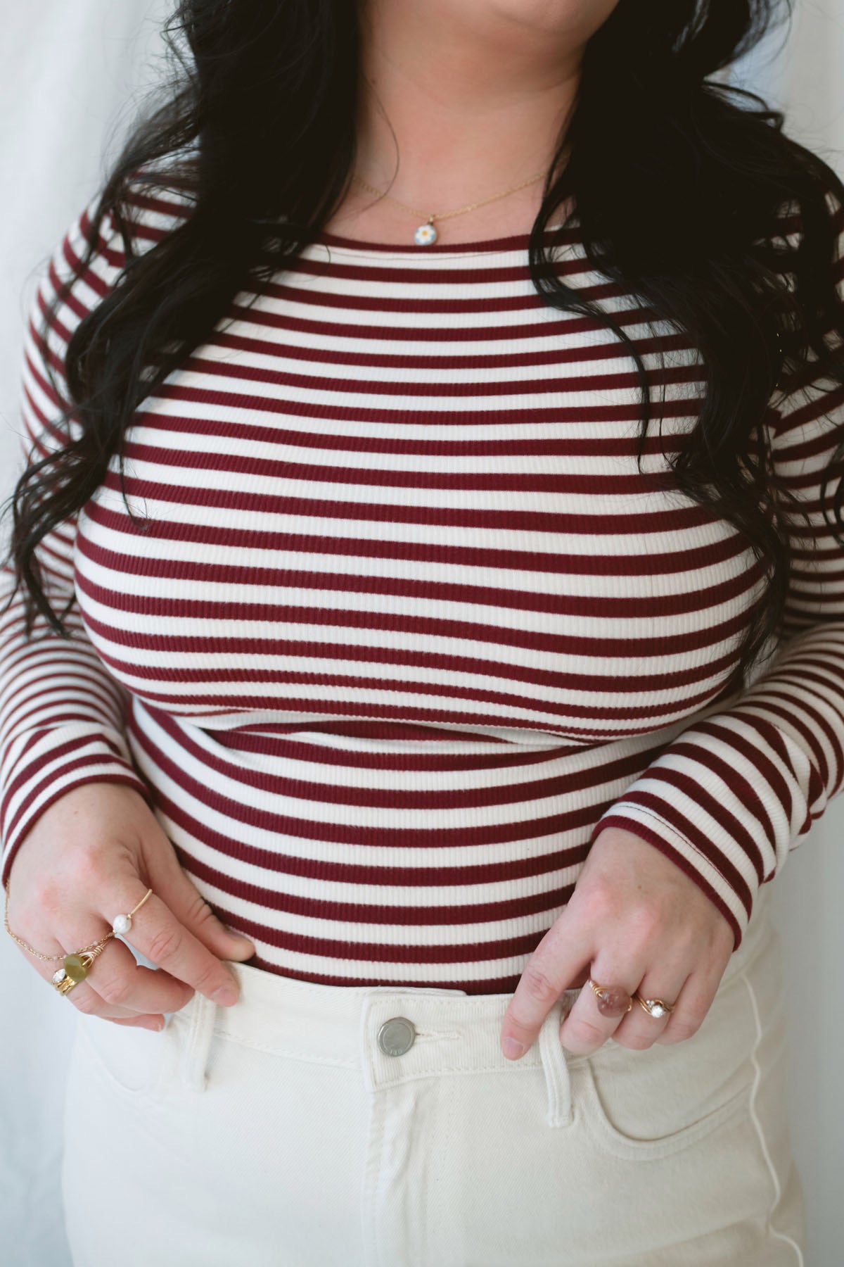 Model wearing long sleeve boat neck style striped top. 