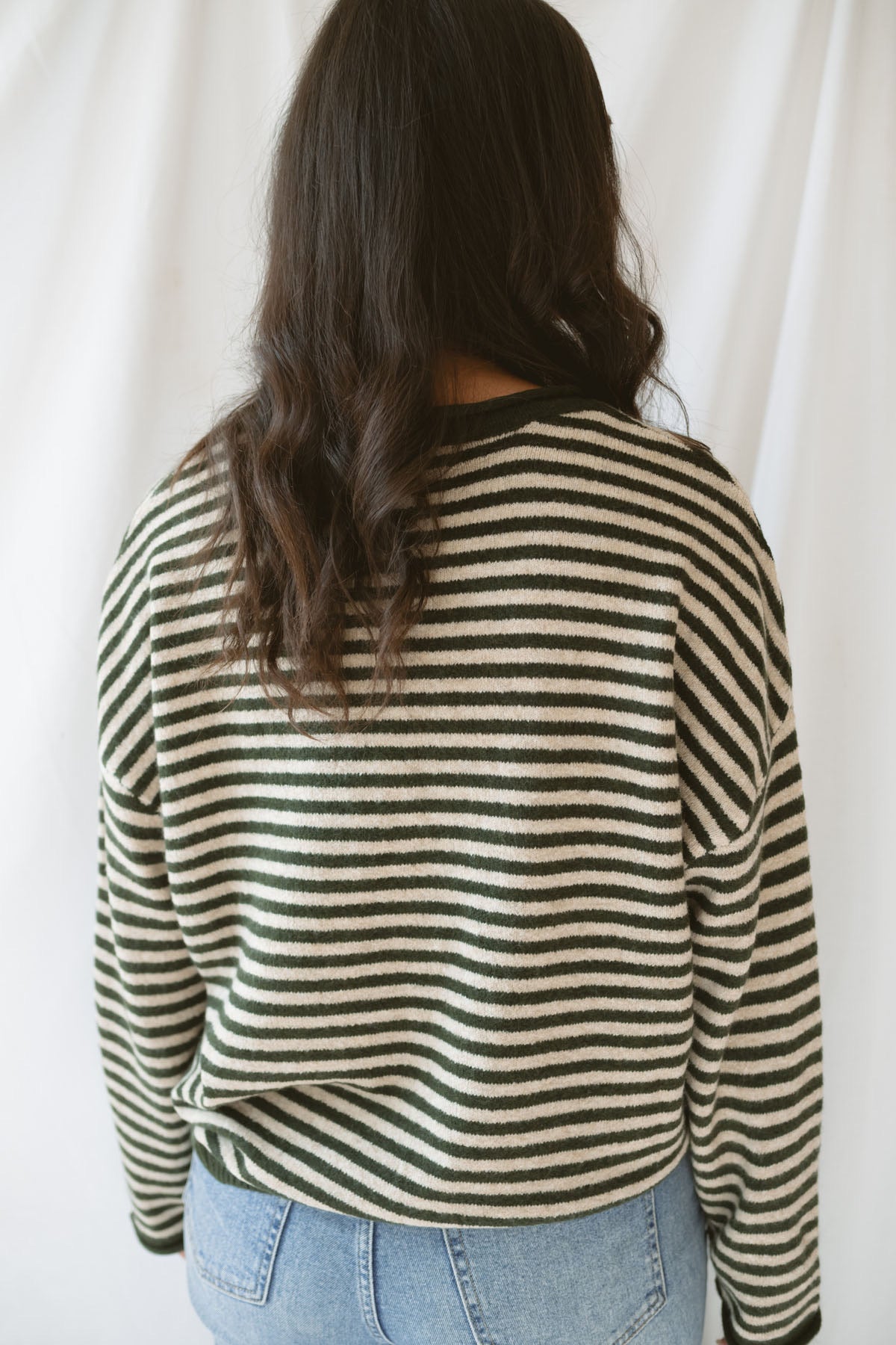 Model wearing the olive striped long sleeve henley sweater. 