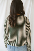 Model wearing the olive striped long sleeve henley sweater. 