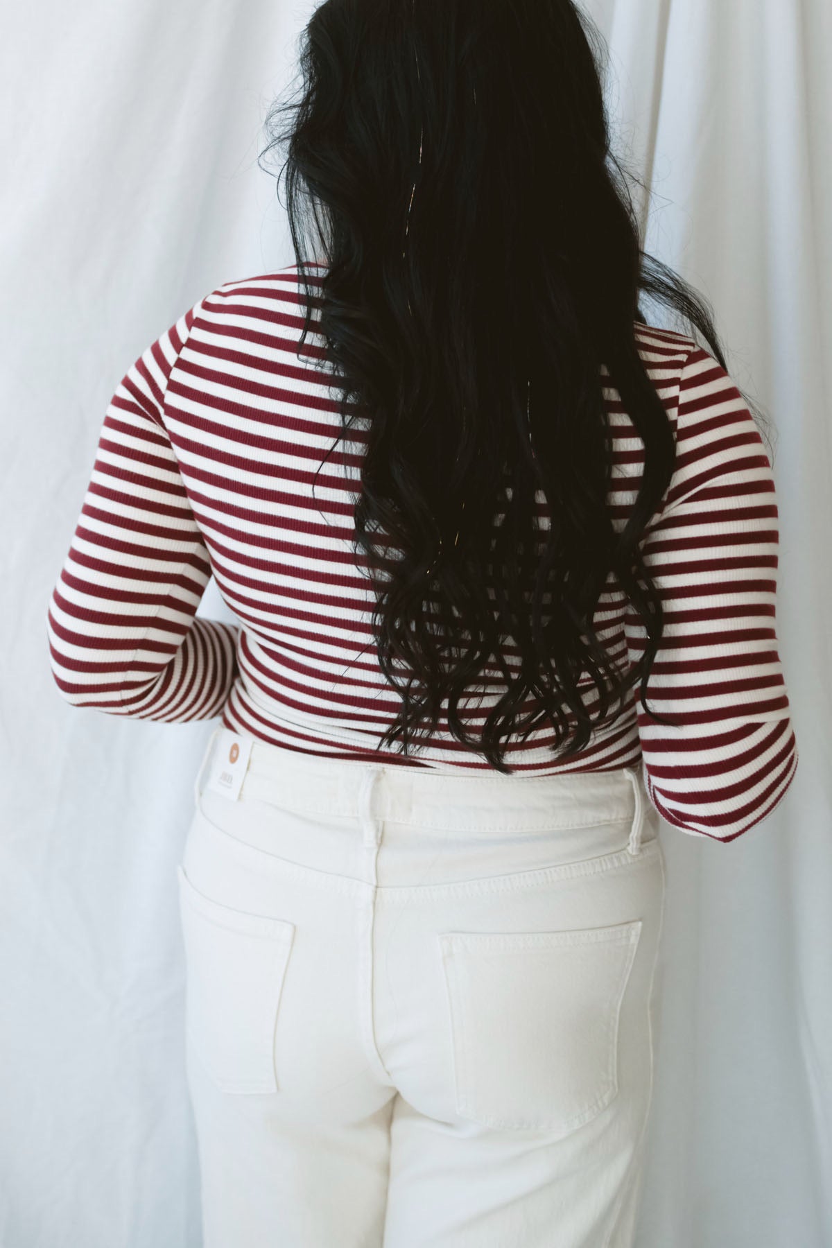 Model wearing long sleeve boat neck style striped top. 