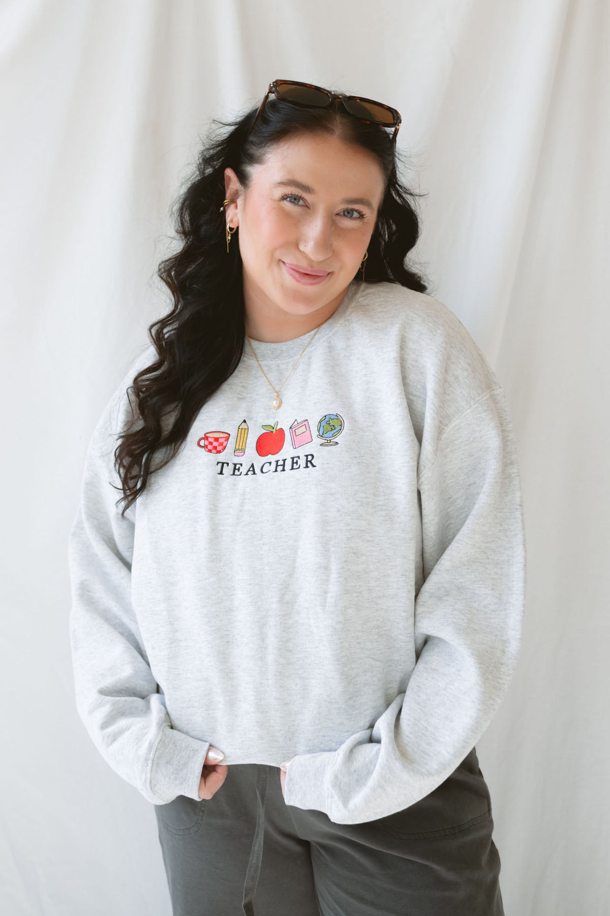 Model wearing the Teacher embroidered icons sweatshirt. 