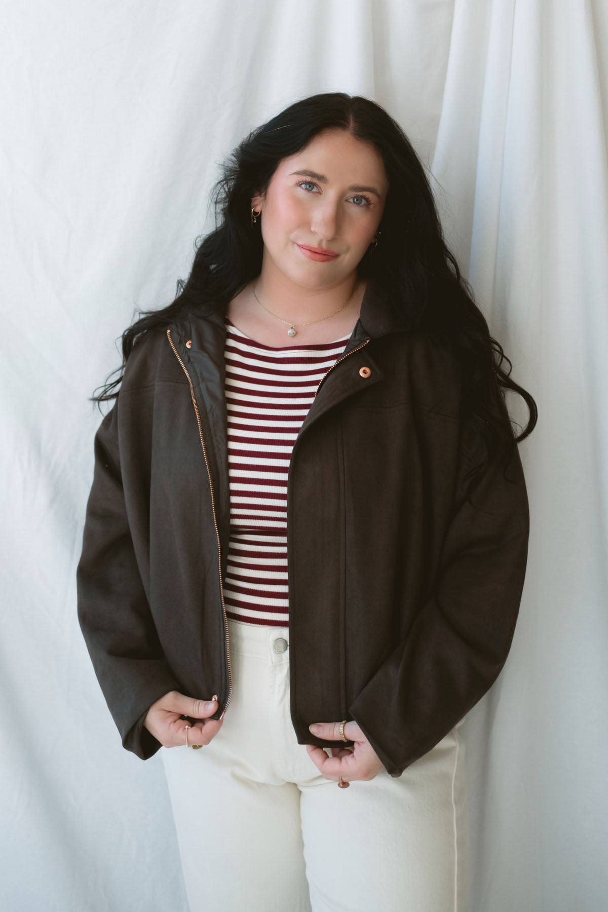 Model is wearing the suede bomber jacket in coffee brown. 