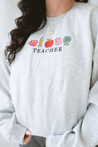 Close up of the icons on the Teacher embroidered sweatshirt 