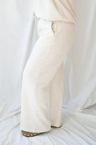 Woman wearing a light beige lounge set with crew neck sweatshirt and drawstring pants on a white background 