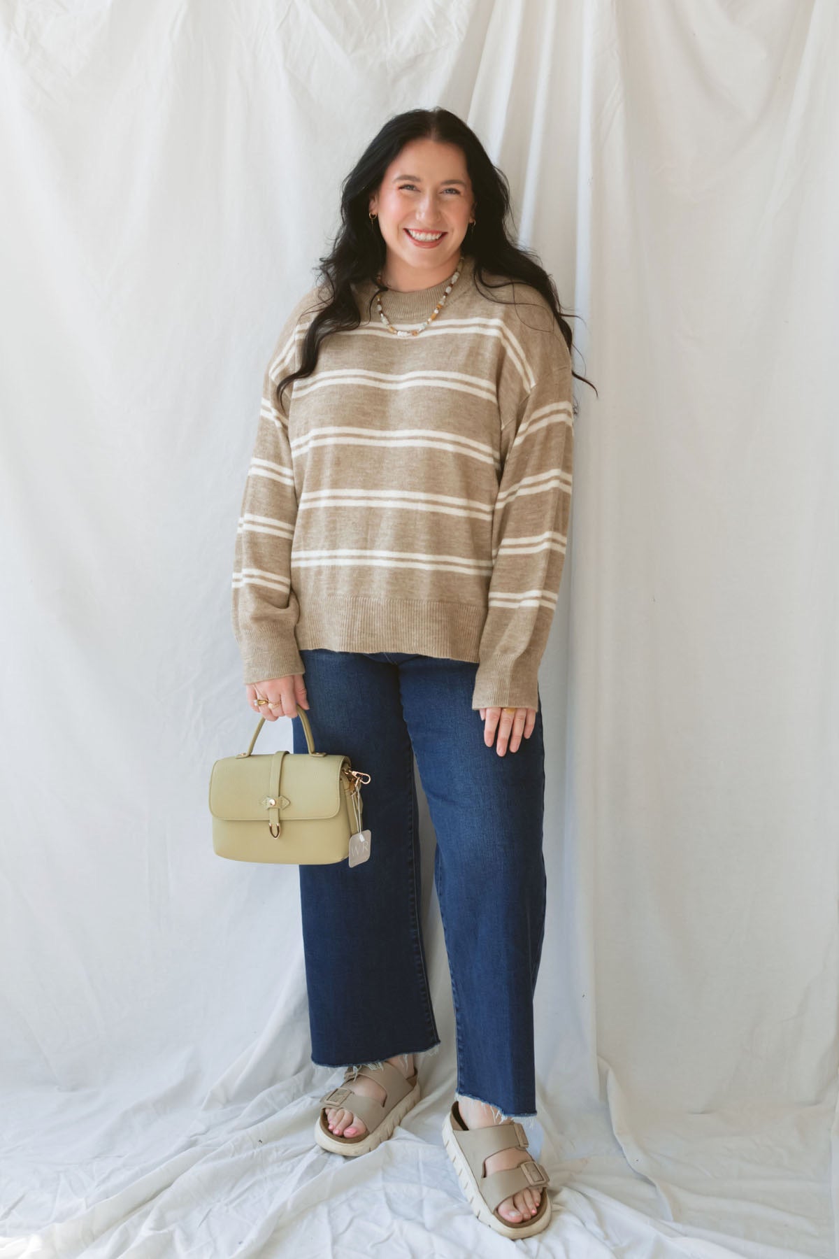 Model wearing the stripe drop sleeve crew neck sweater in mocha. This is perfectly oversized and great to pair with a variety of pants. 